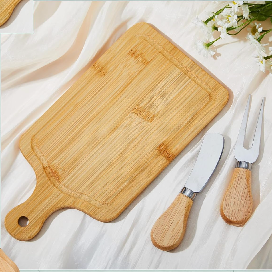 Bamboo cutting board with engraved text on a white fabric background, accompanied by two wooden-handled knives.
